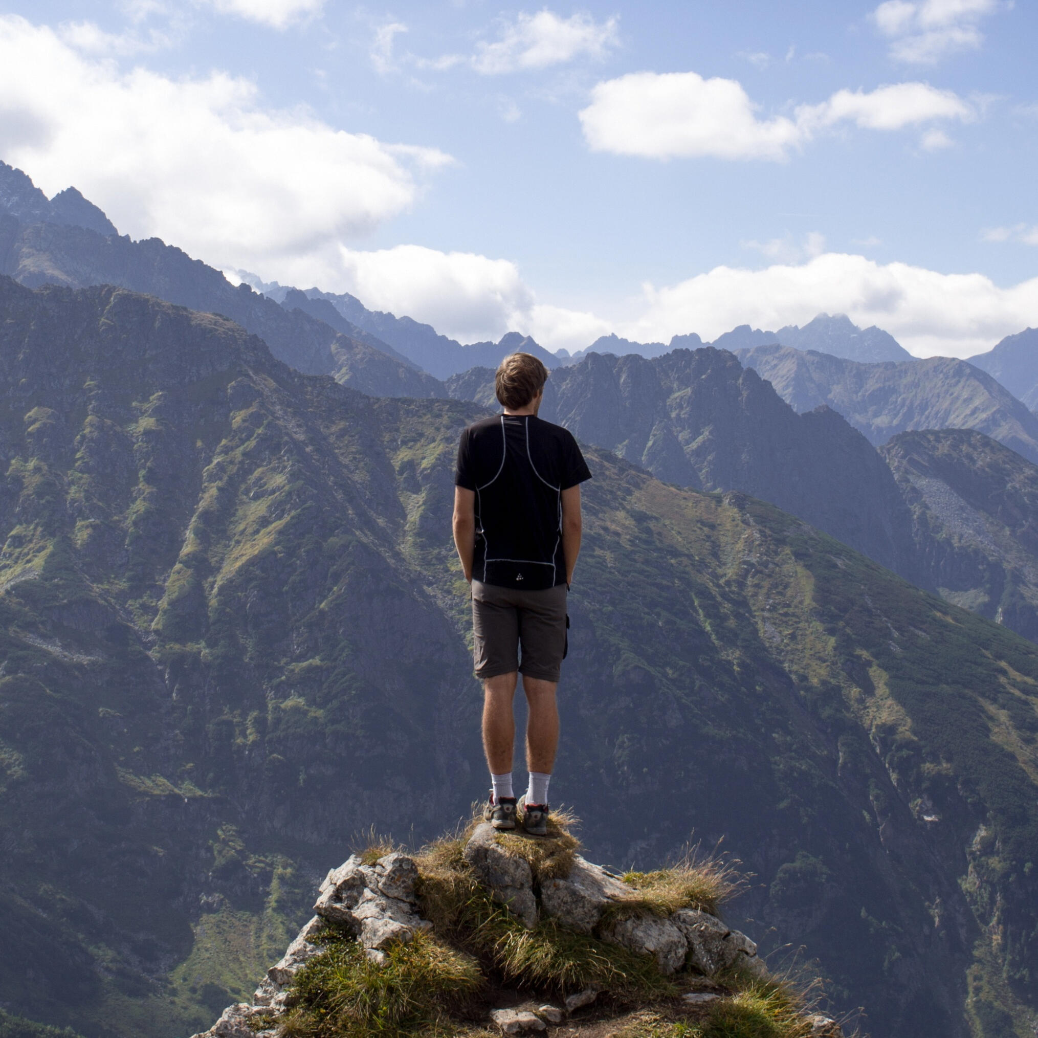 Man On the Mountain A man standing on the edge of a cliff looking out over the rugged terrain before him.